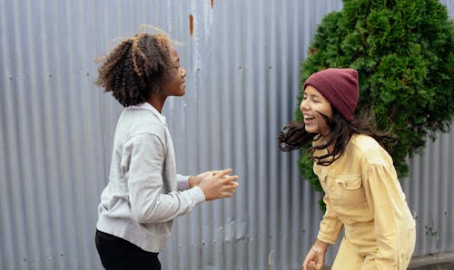 Side view of multiracial girls smiling while having fun together in backyard of house