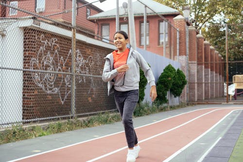 Free Hispanic girl running on sports ground Stock Photo