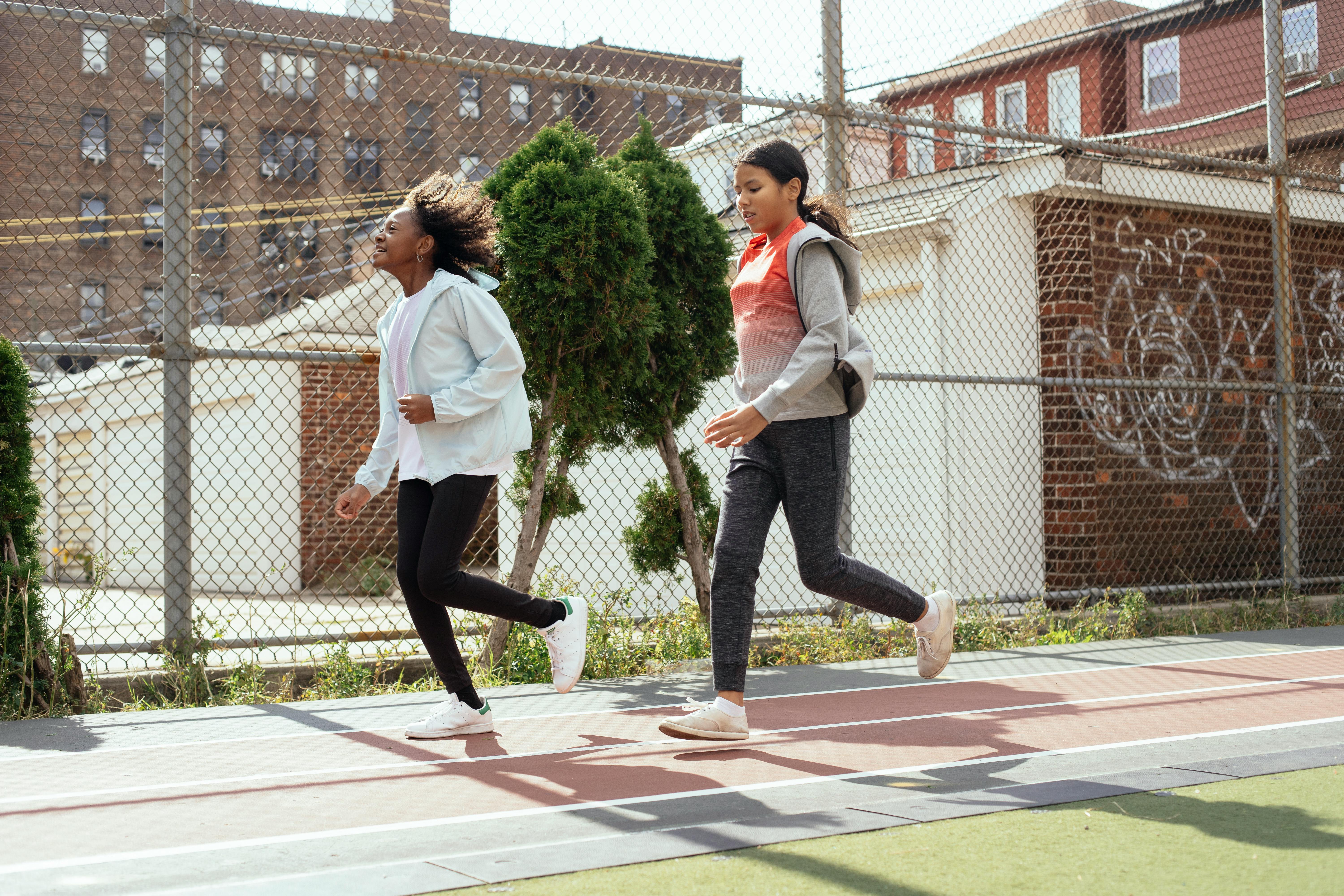 diverse schoolgirls running on stadium together