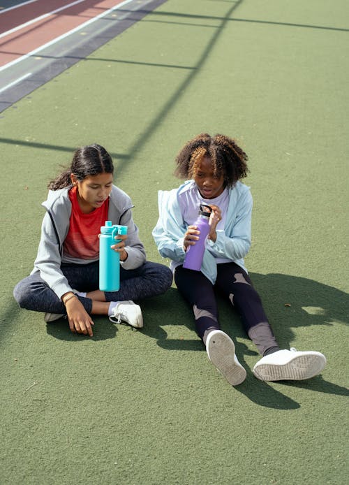 Ragazze Multietniche Con Bottiglie Di Plastica Sul Campo Sportivo