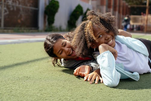 Free Diverse children in casual clothes lying on sports ground while having fun together during weekend Stock Photo