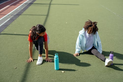 Ragazza Nera Che Fa Spaccatura Mentre Amico Che Allunga Prima Dell'allenamento Allo Stadio