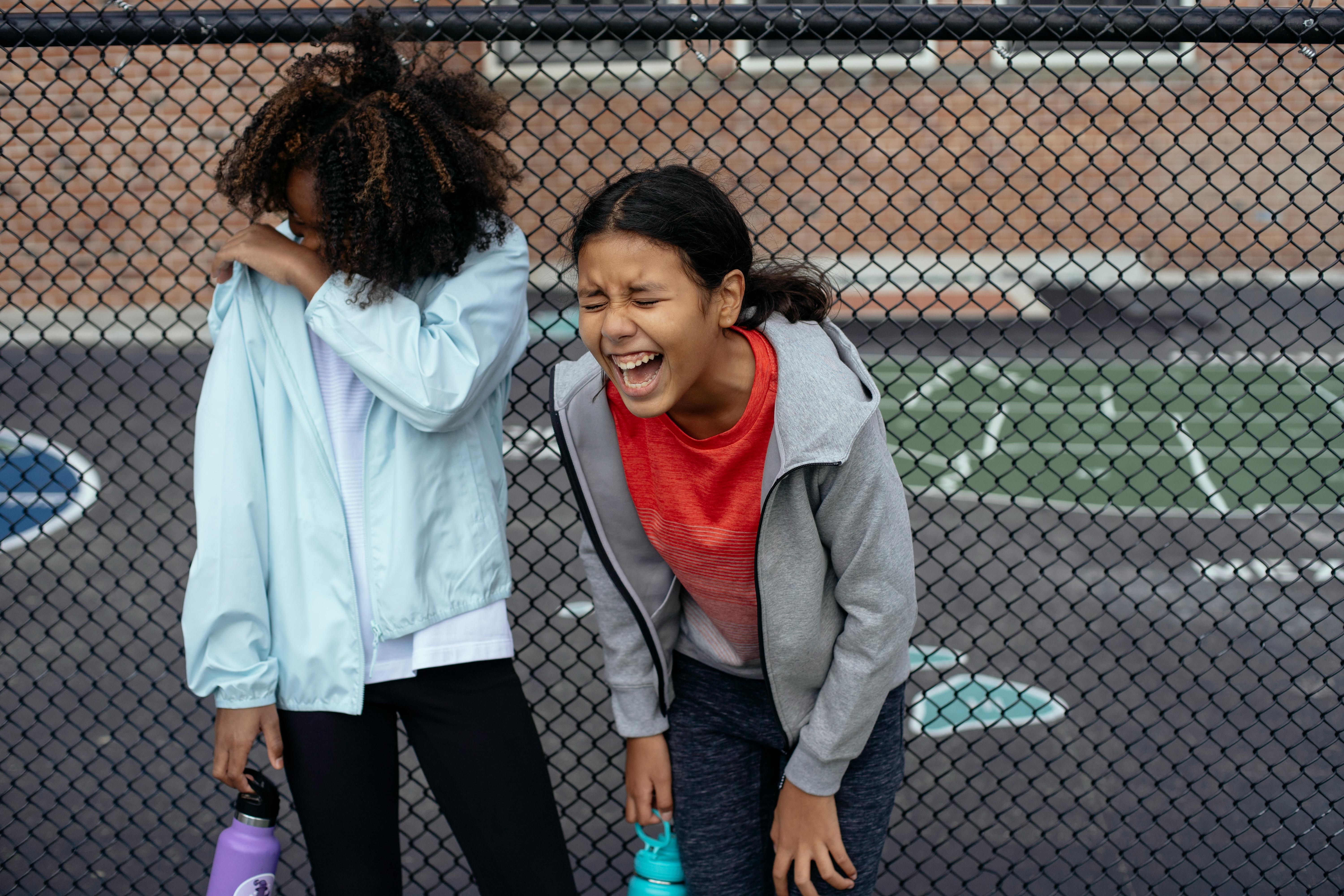 multiethnic schoolgirls laughing on sports ground