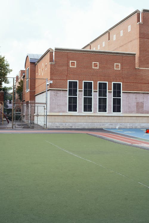 Exterior of  red brick building of school with sports ground with synthetic grass