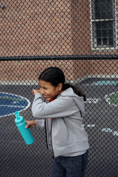 Ragazza Etnica Di Risata Con Una Bottiglia D'acqua