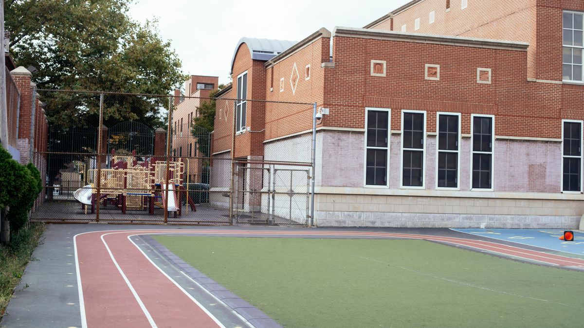 Exterior of contemporary school building made of red brick with empty sports ground