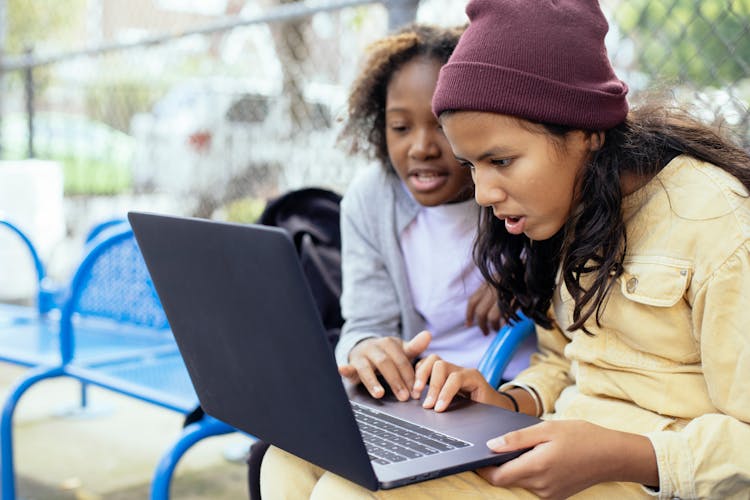 Diverse Girls Using Laptop In Yard