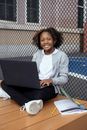 Black student with laptop and textbook