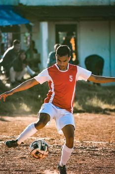 A young man playing soccer outdoors on a sunny day, showing dynamic movement.