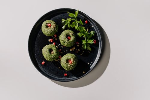 Free Exquisite Georgian spinach pkhali garnished with pomegranate and herbs on a dark plate. Stock Photo
