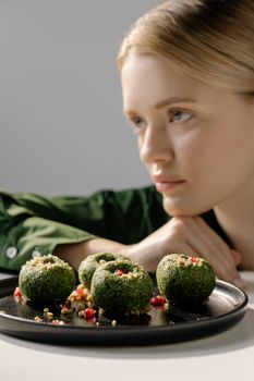 Woman in focus with traditional Georgian spinach dish, vegan and vegetarian.