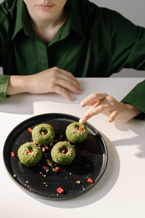 A Person in Long Sleeve Shirt Touching the Food on the Table