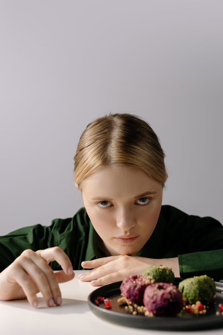 A Woman Looking At Camera With Food On The Table In Front Of Her