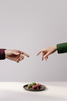 A minimalist image showcasing Georgian pkhali on a plate with hands reaching out, highlighting vegan cuisine.