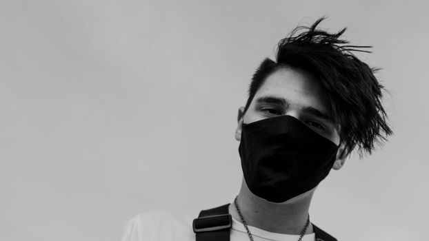 男子戴口罩的黑白时尚肖像，展现城市街头服饰风格