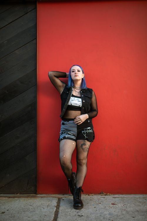 Free Stylish woman with purple hair poses confidently against a vibrant red wall. Stock Photo