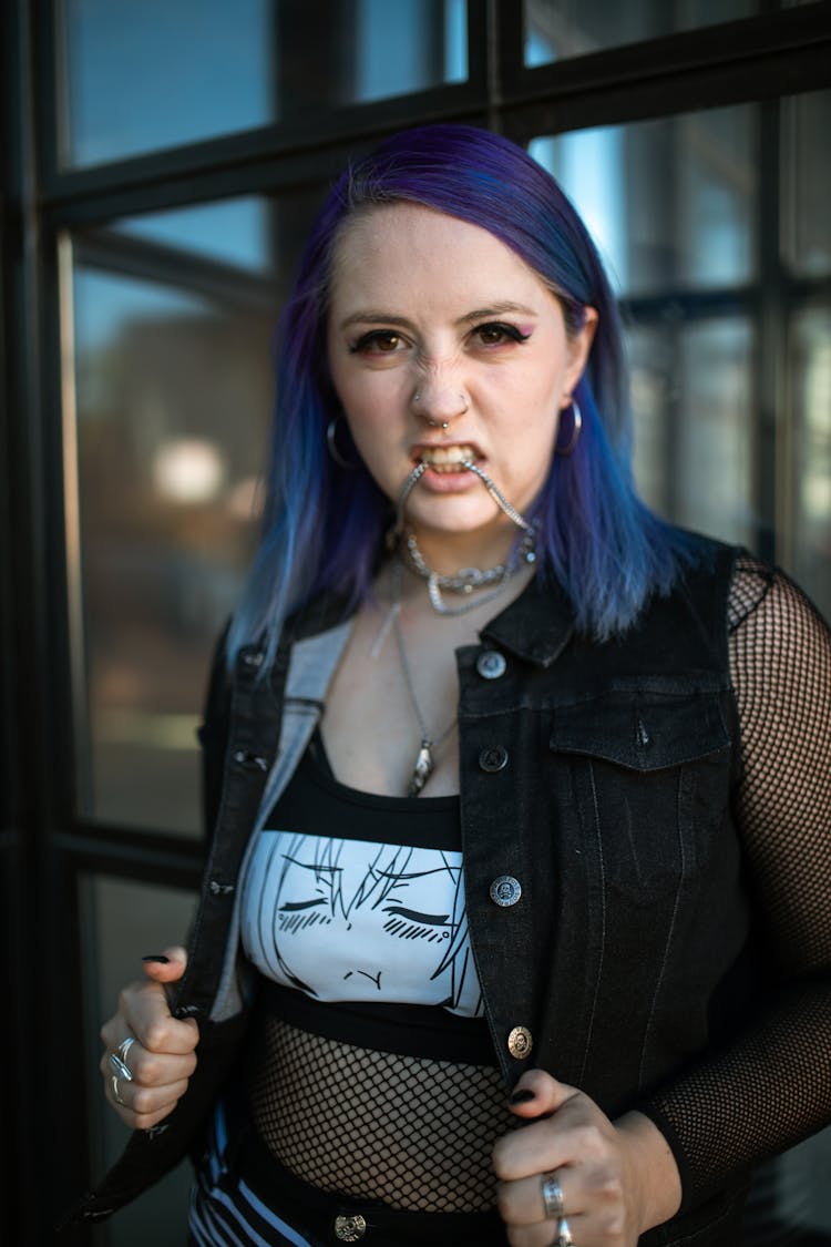 Woman With Purple Hair Biting Her Necklace While Looking At The Camera