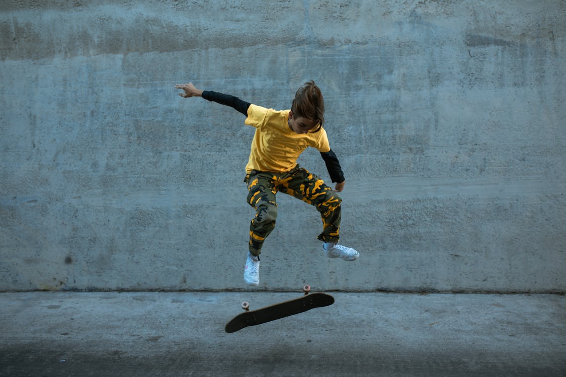 Free Person in Yellow Shirt Jumping on the Skateboard Stock Photo