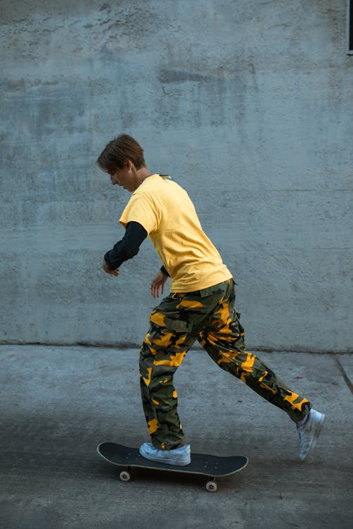 Gratis Niño Con Camiseta Amarilla Y Pantalones De Camuflaje Negros Y Amarillos Corriendo En La Carretera Foto de stock