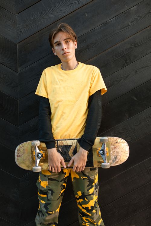 Free Portrait of a stylish skater holding a skateboard, showcasing urban street fashion. Stock Photo