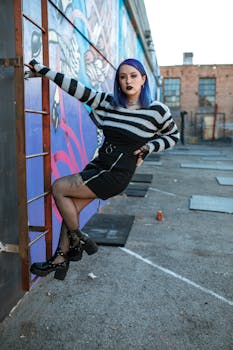 Stylish young woman poses against graffiti wall in urban setting.