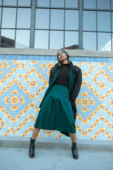 Model in stylish outfit posing against a vibrant geometric backdrop, showcasing street fashion flair.