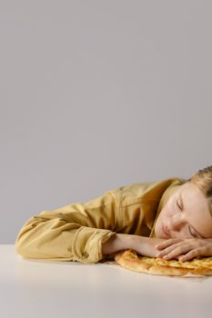 一名年轻女子穿着黄色夹克，在中性背景的披萨上睡着了