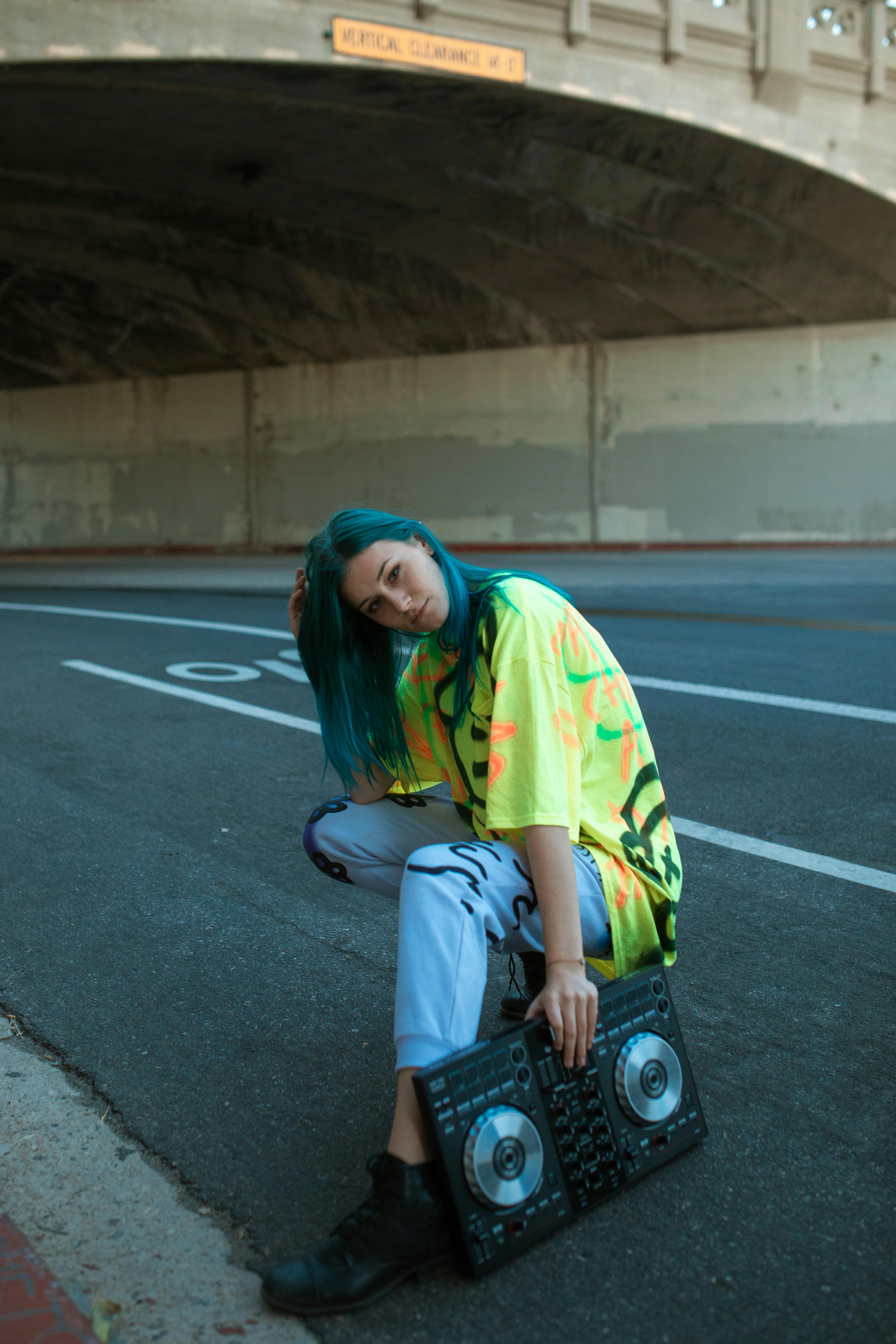 woman in green t shirt and blue denim jeans sitting on road