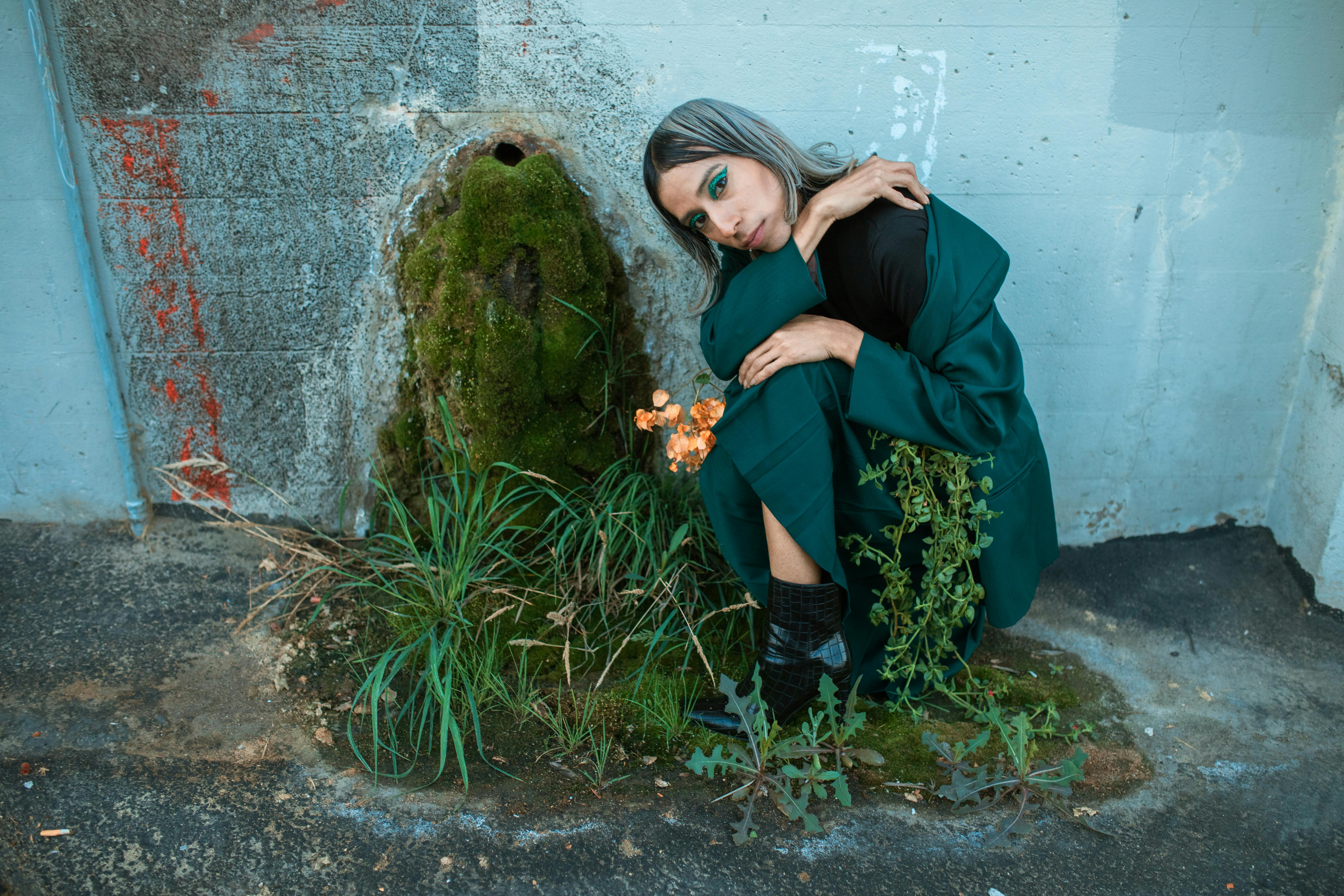 woman in black jacket and blue denim jeans sitting on rock