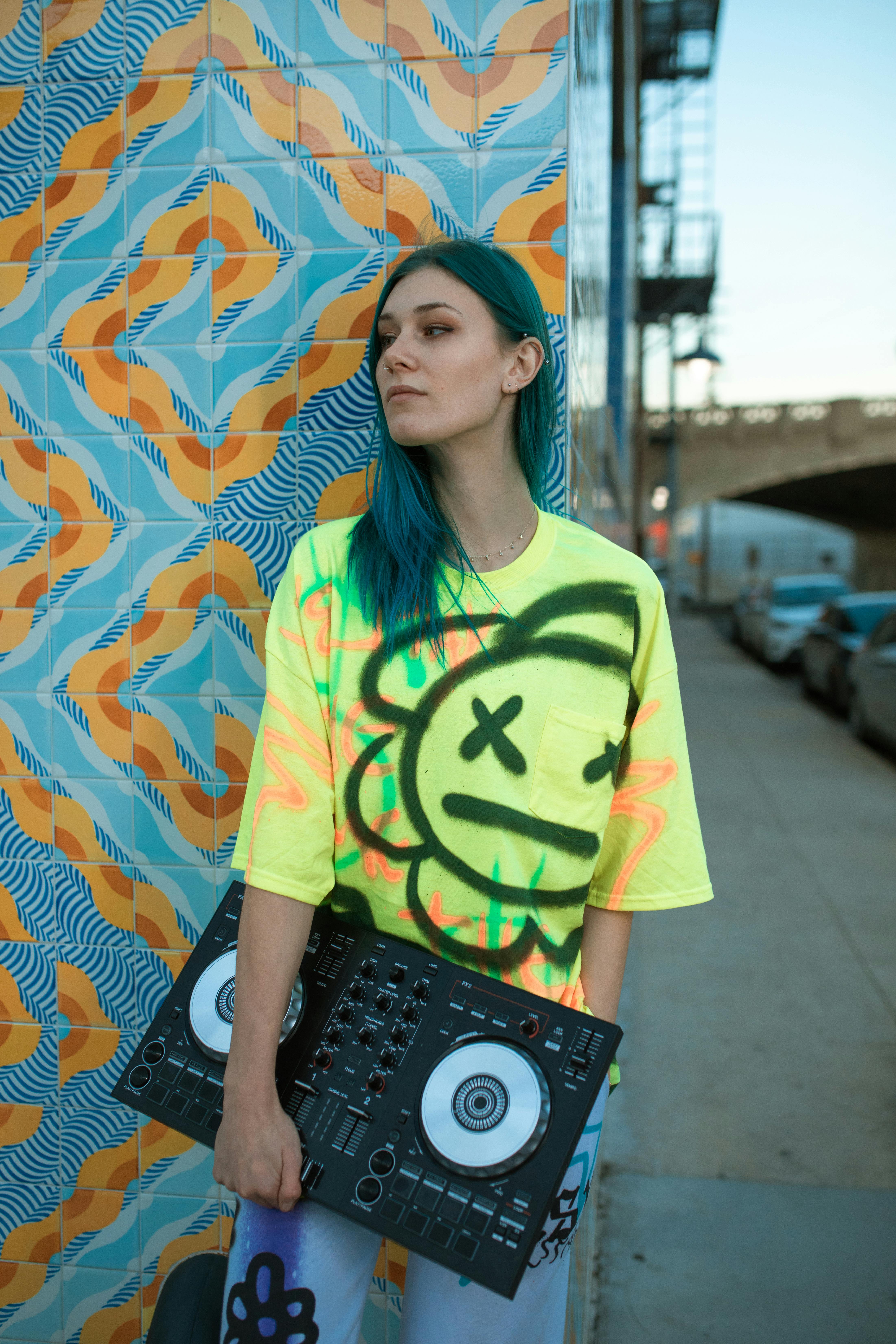 woman in green and white t shirt standing beside wall with graffiti