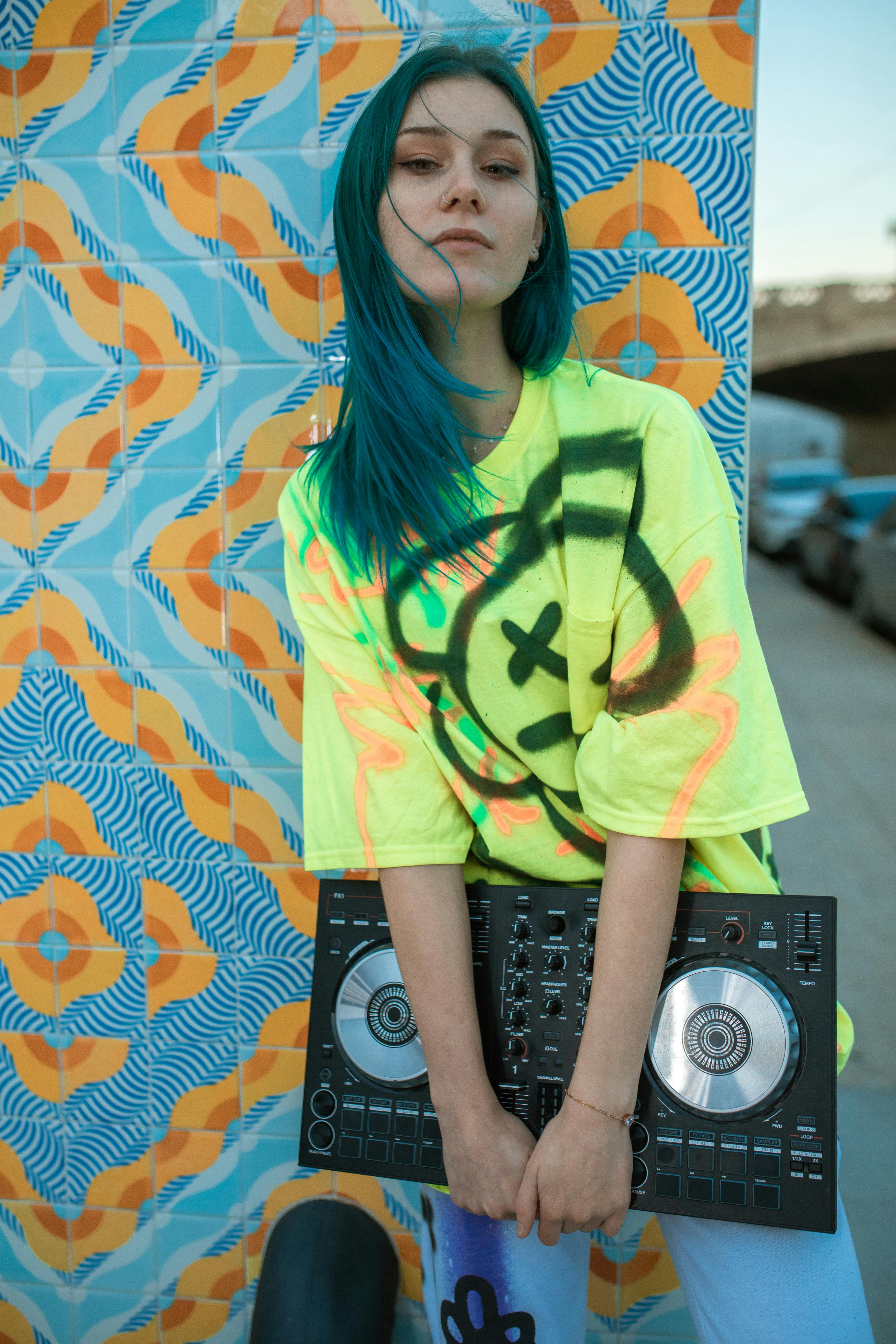 woman in yellow and green crew neck t shirt standing beside black and gray speaker