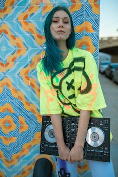 Fashionable young DJ with blue hair, mixing in funky urban setting.