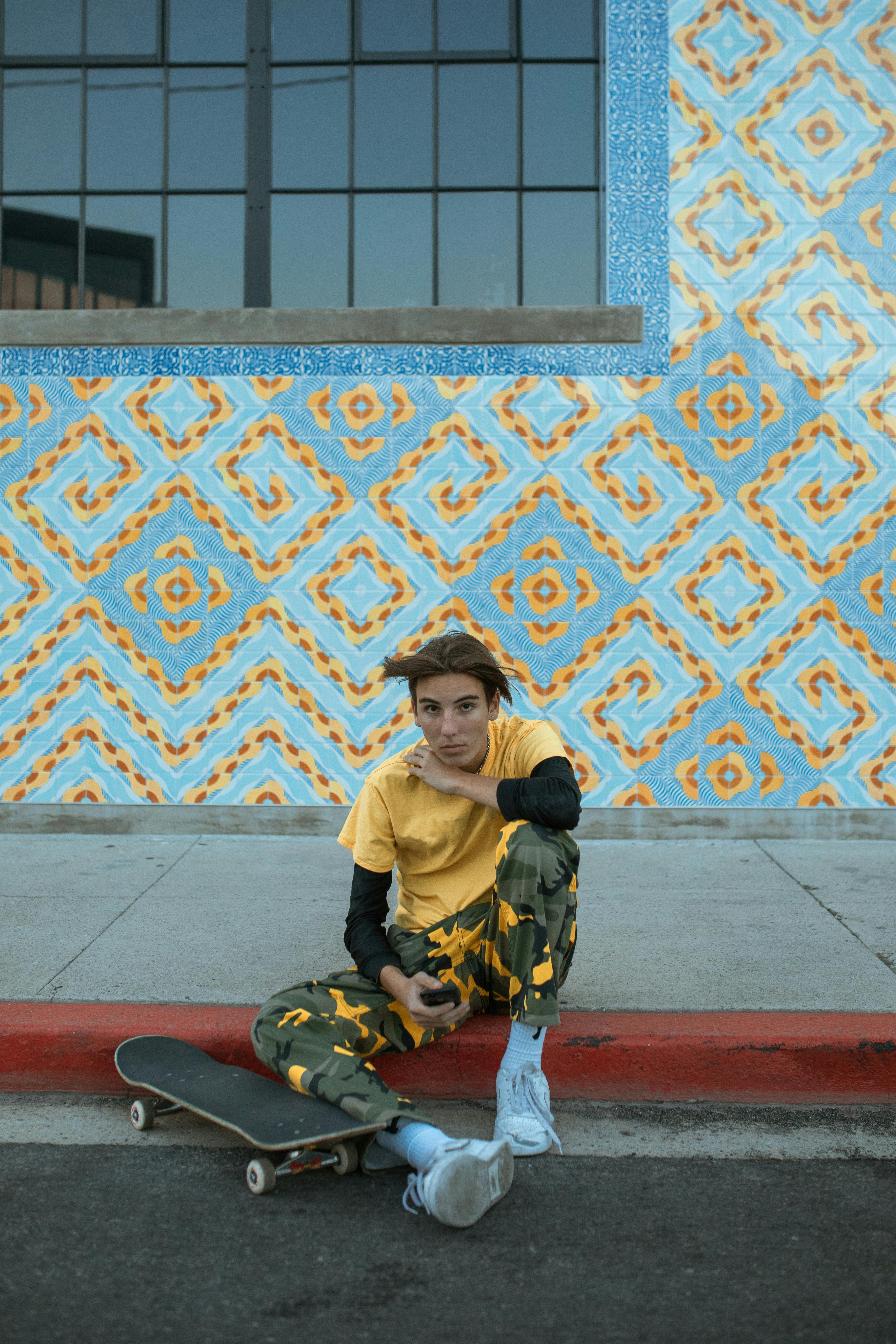 boy in yellow crew neck t shirt and black pants sitting on red and brown concrete