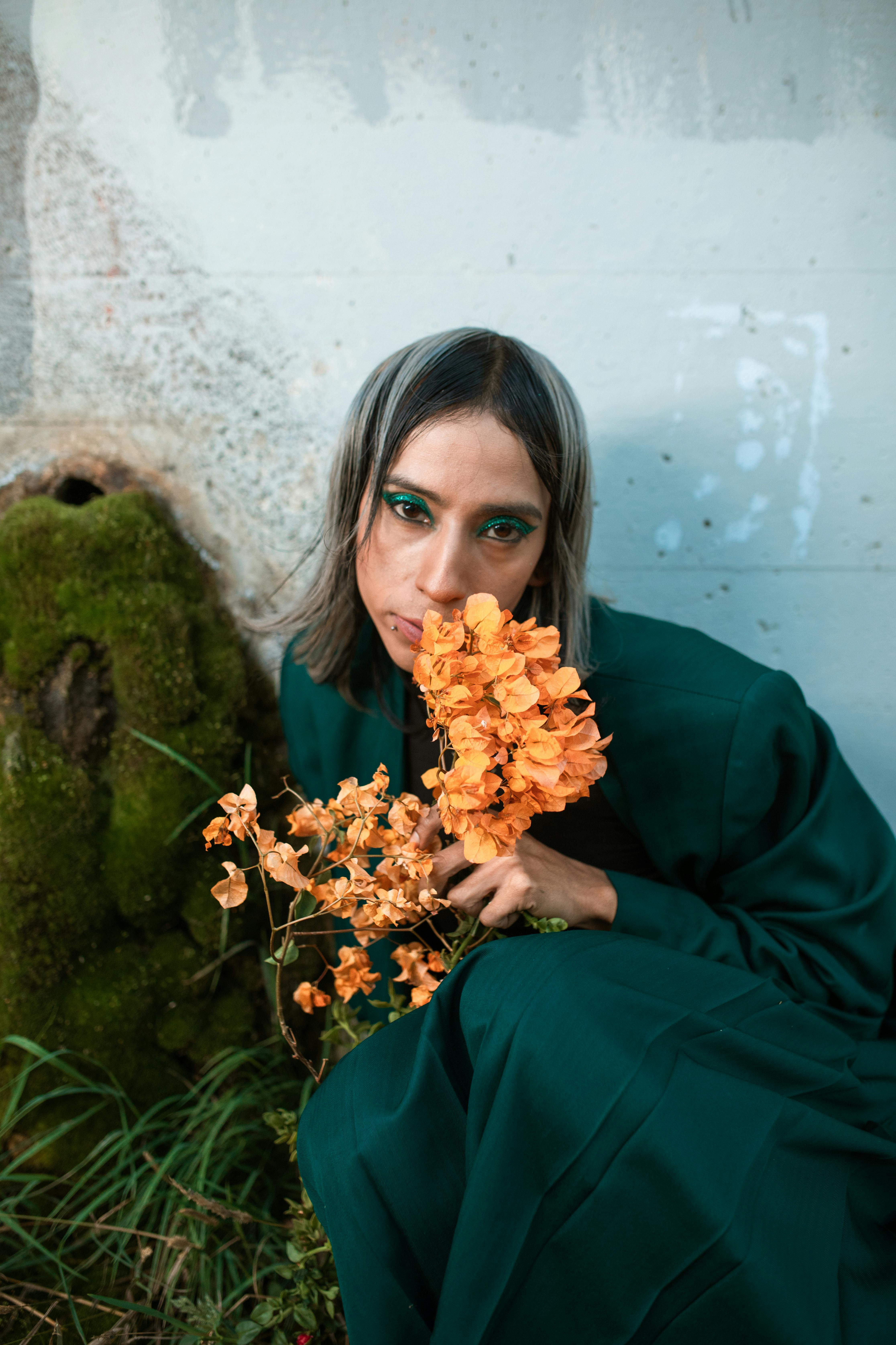 woman in blue long sleeve shirt holding yellow flower