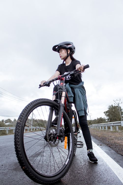 Free A woman cyclist wearing a helmet rides a bike on a country road. Stock Photo