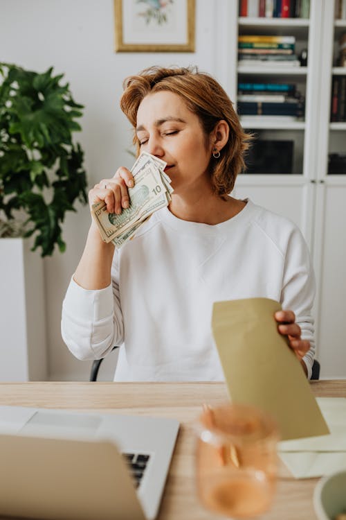 Pretty Woman Smelling Money and Holding a Envelope