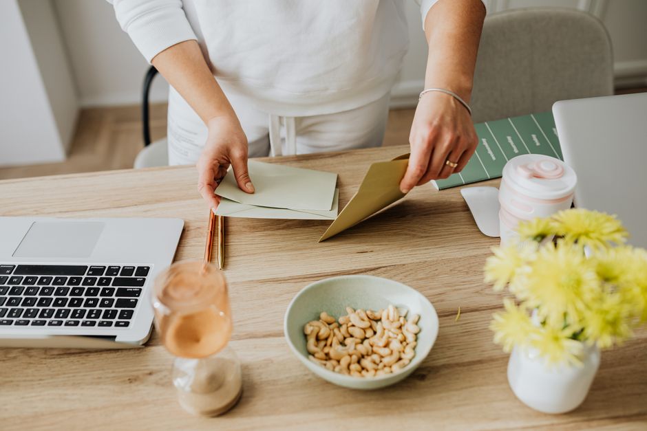 Does Pre-Workout Actually Boost Performance? Science-Based Review A woman arranges envelopes on a desk with a laptop, cashews, and flowers.