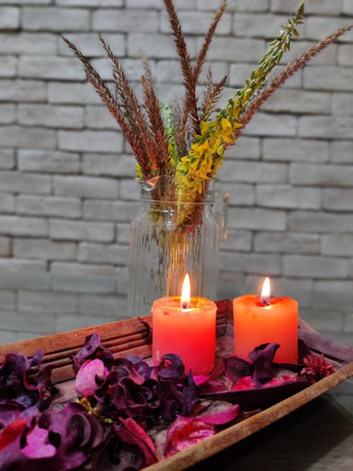 Burning Candles next to Flowers in a Vase