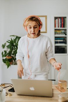 Woman wearing headphones and engaging with a laptop in a modern home setting.