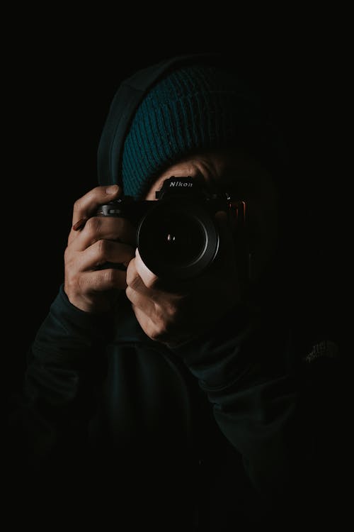 Unrecognizable photographer using photo camera in dark room
