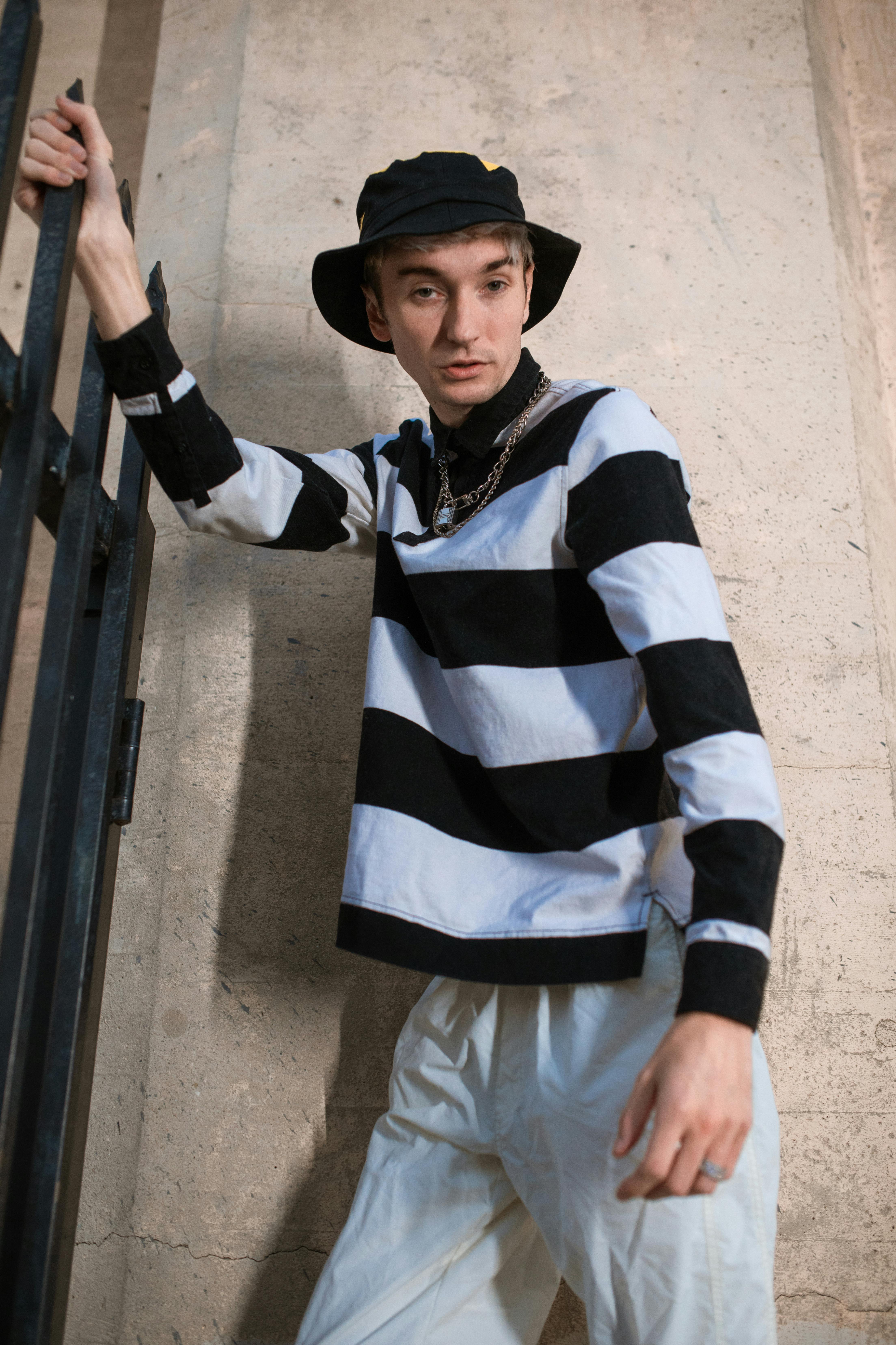 man in black and white striped long sleeve shirt and white pants wearing black hat