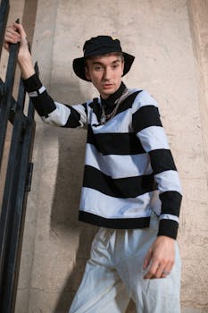 Stylish young adult in black and white stripes poses outdoors, exuding modern street fashion vibes.