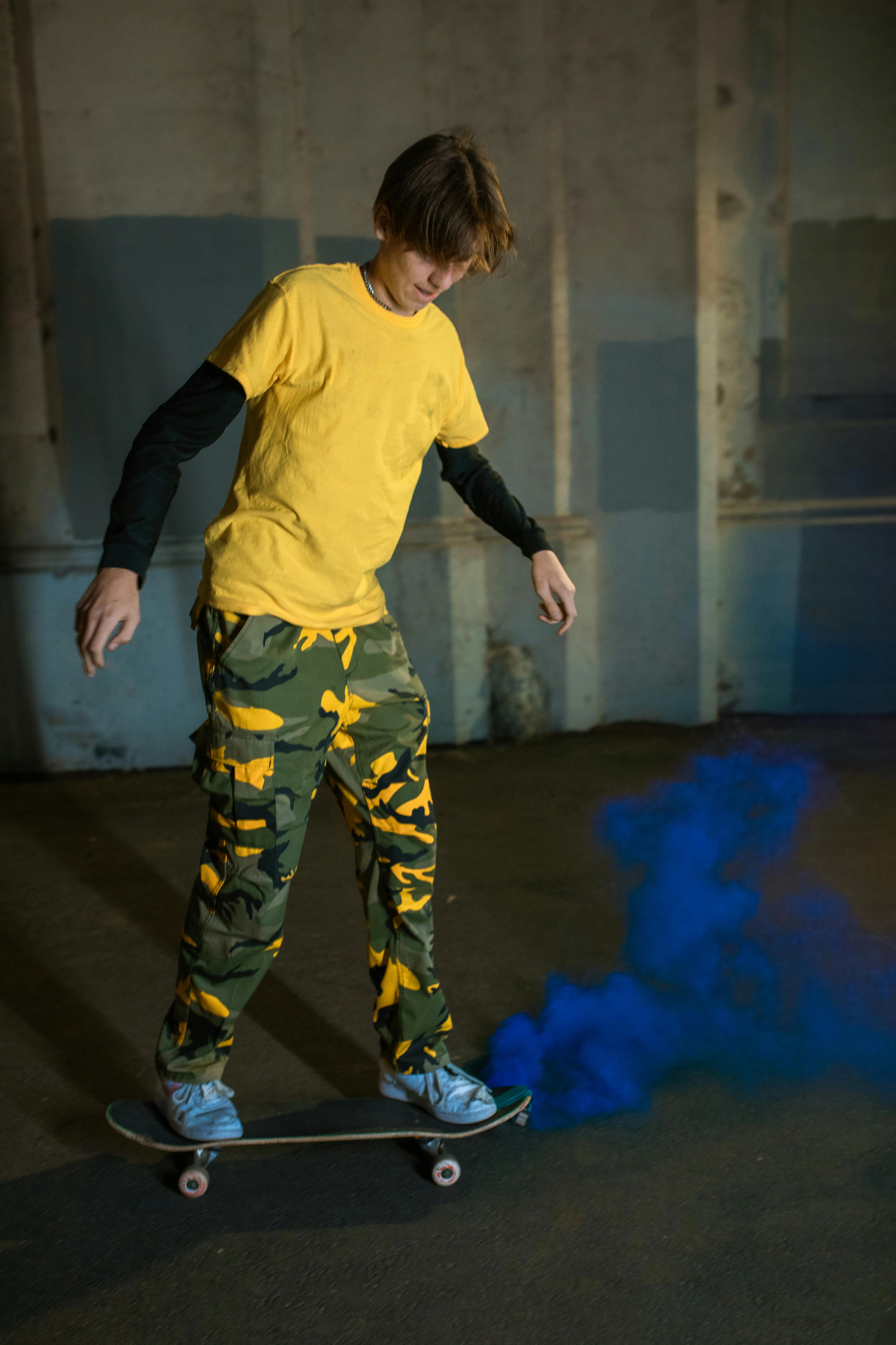 boy in yellow long sleeve shirt and green pants standing on brown wooden floor