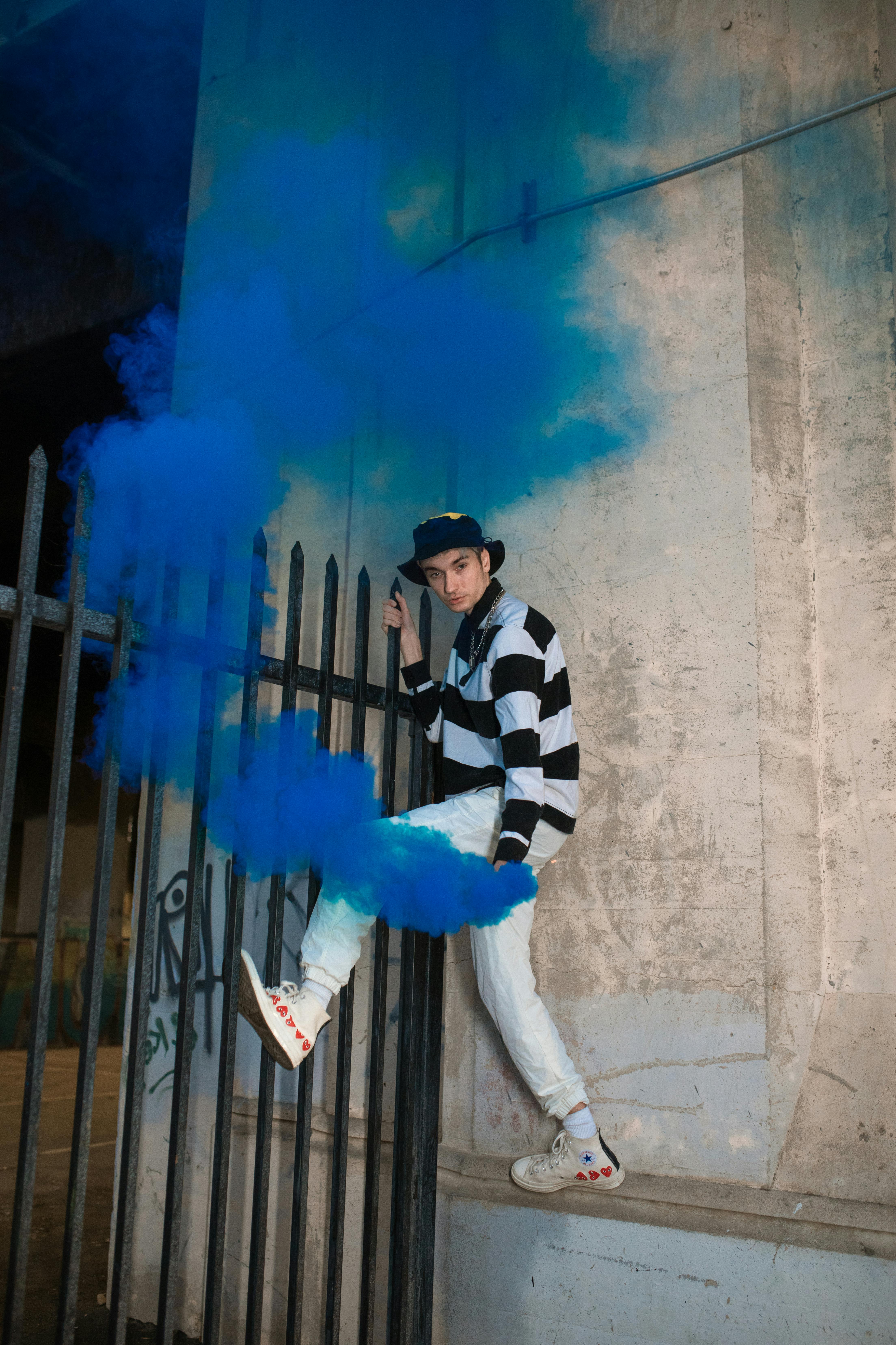 man in black and white striped long sleeve shirt holding blue smoke