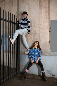 Young duo showcasing vibrant street fashion against gritty urban backdrop.