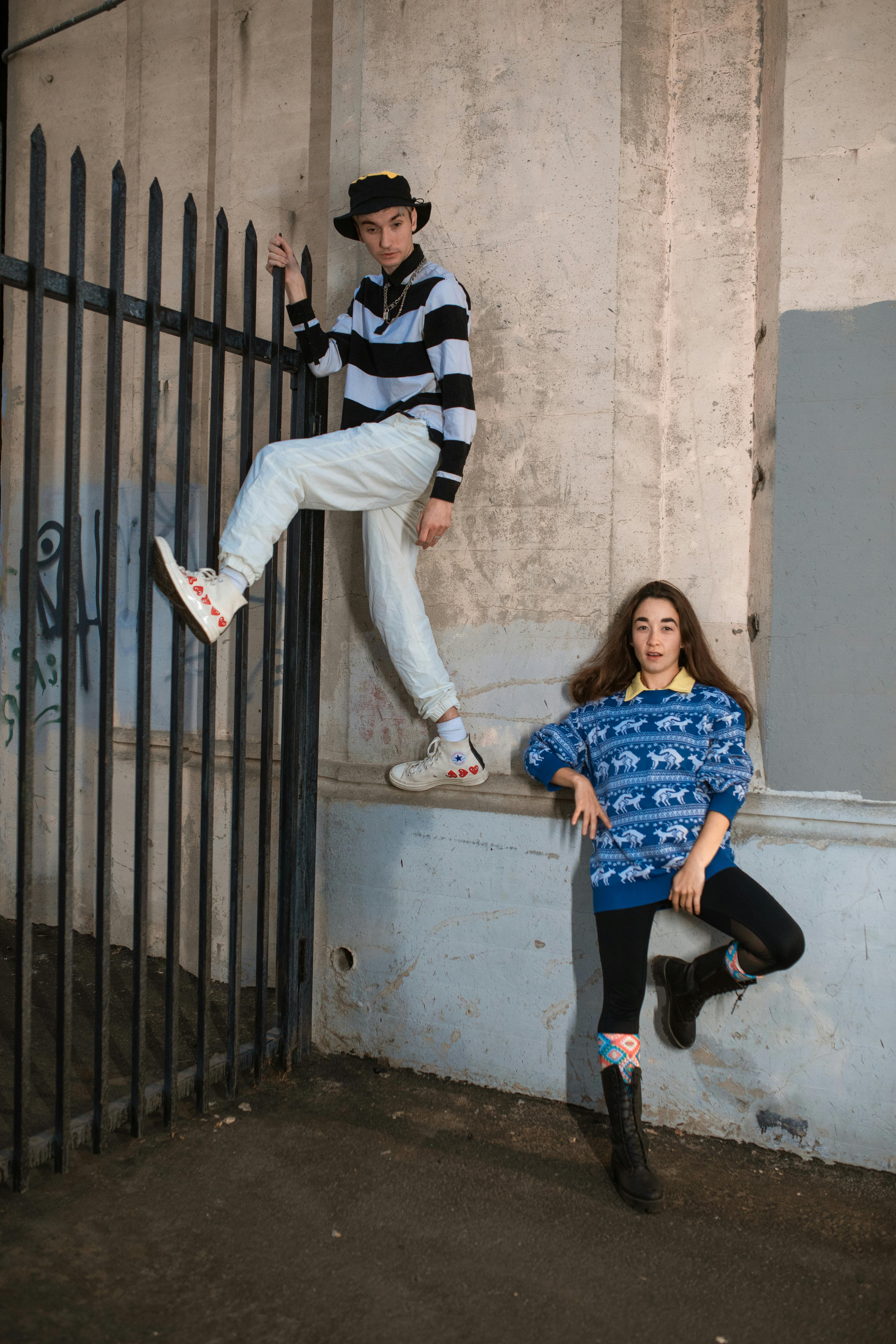 woman in blue and white polka dot shirt and white pants sitting on black metal gate