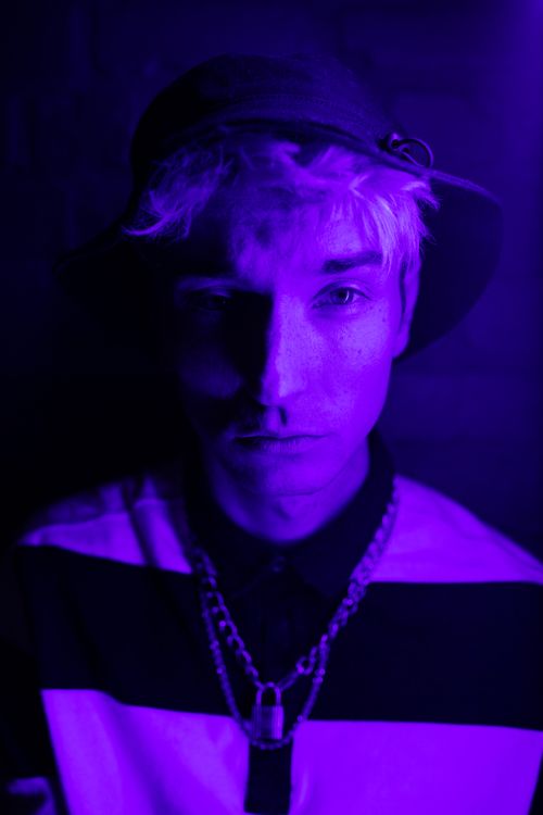Free A striking portrait of a young adult under violet lighting, creating a mysterious ambiance. Stock Photo