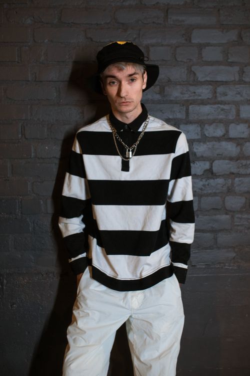 Free Stylish young adult in monochrome outfit with striped sweater and bucket hat against brick wall. Stock Photo