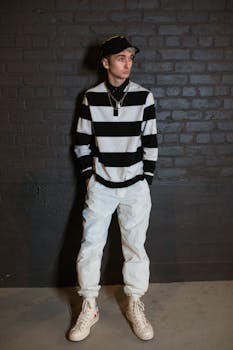 Trendy young adult wearing a striped black and white outfit, posing against a brick wall.