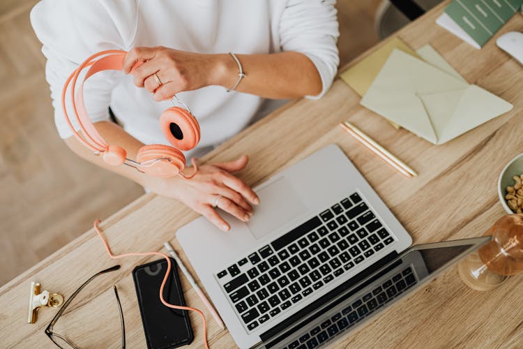 Woman Using A Laptop And Holding Headphones In Hand 